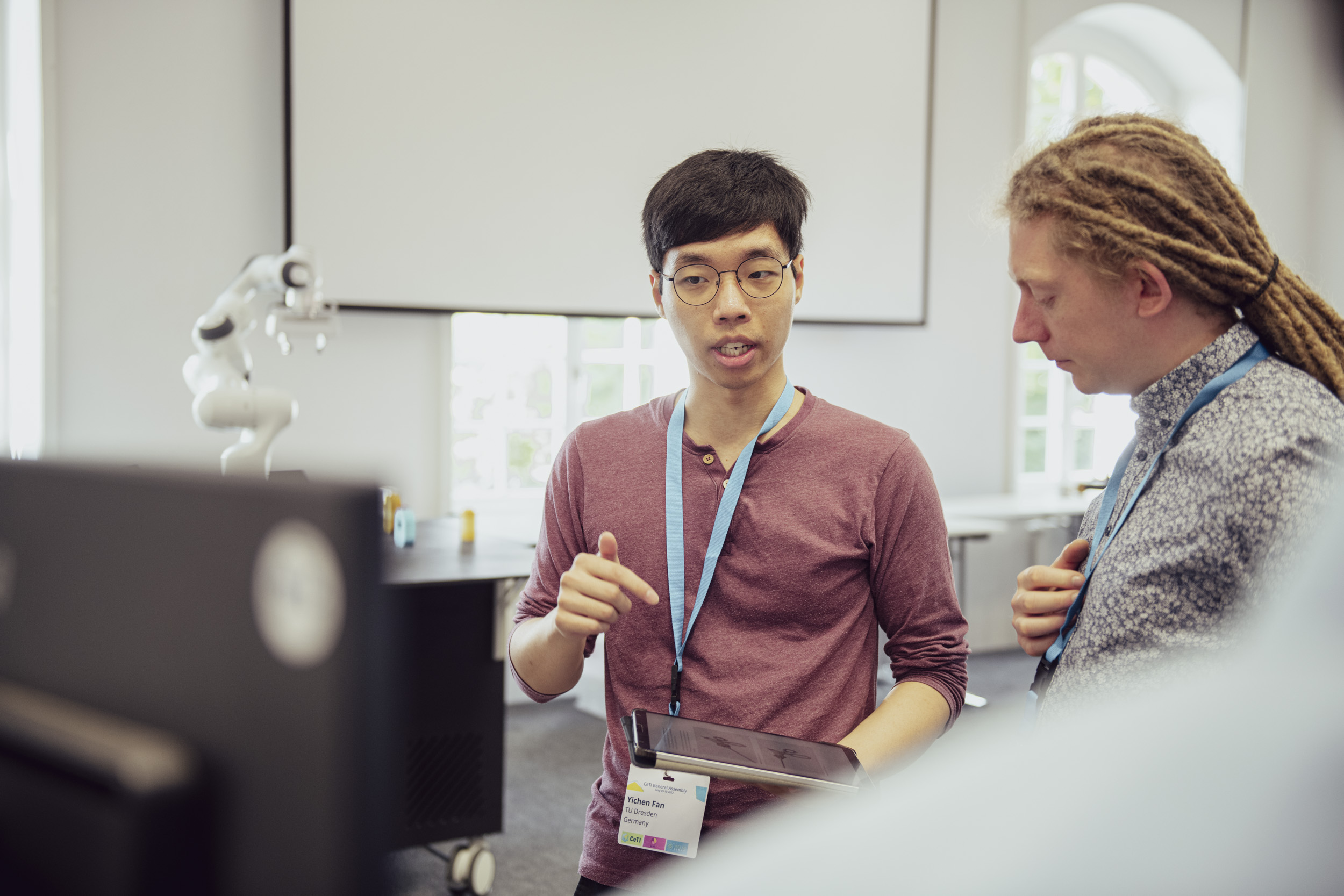 Two researchers talking, one of them holding a tablet