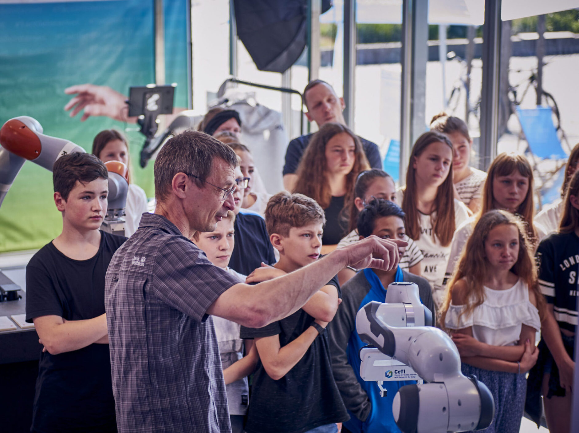 Picture of a group of children listening to a researcher's explanation of robotic arms