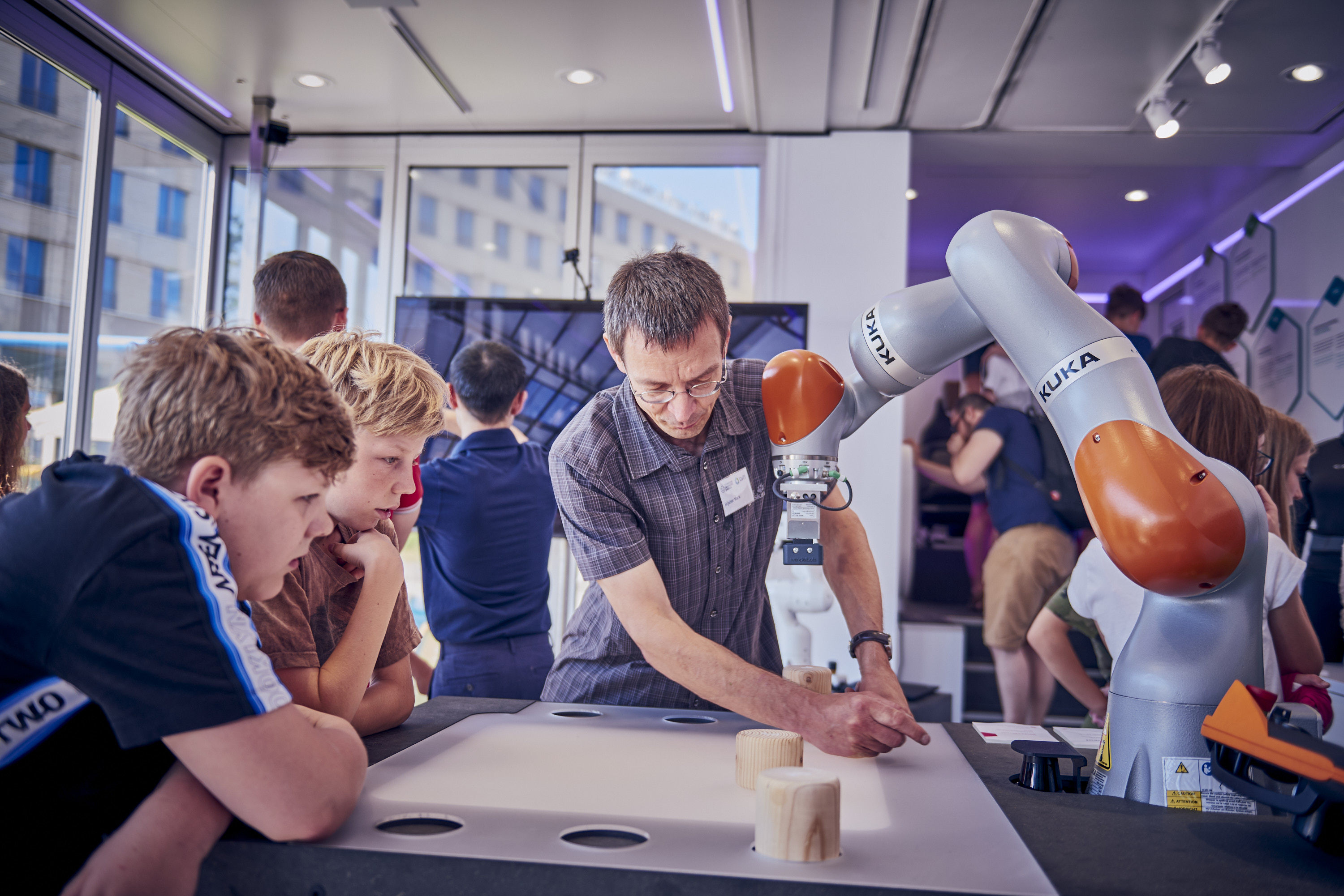 Image of a researcher explaining a robotic arm to children