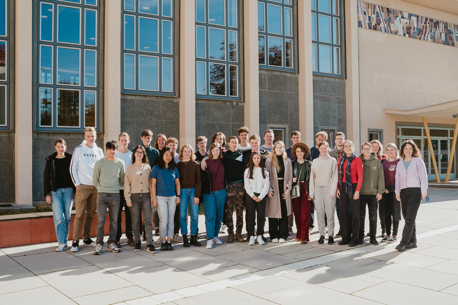 Photograph of a big group of boys and girls standing in front of a TU Dresden building