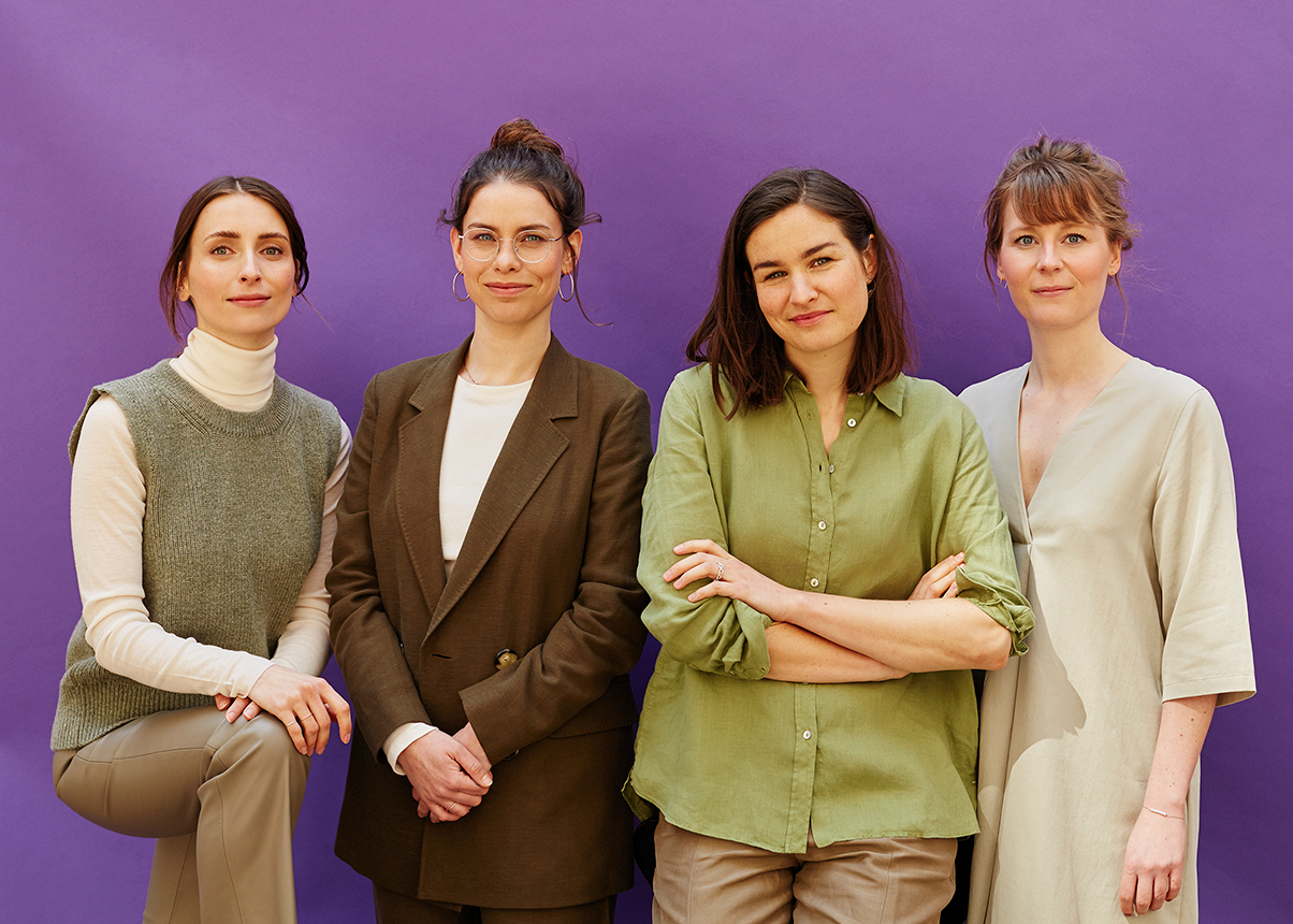 image of four women with a purple wall behind