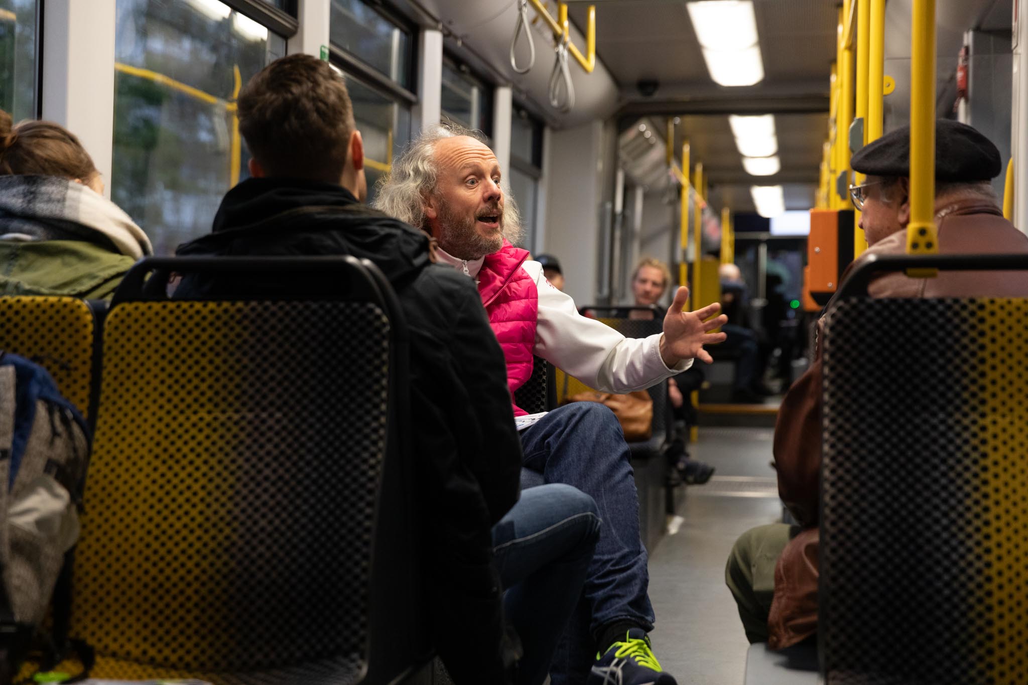 Picture of the Science Tram event - showing a man giving a presentation to others sitting around him on the tram