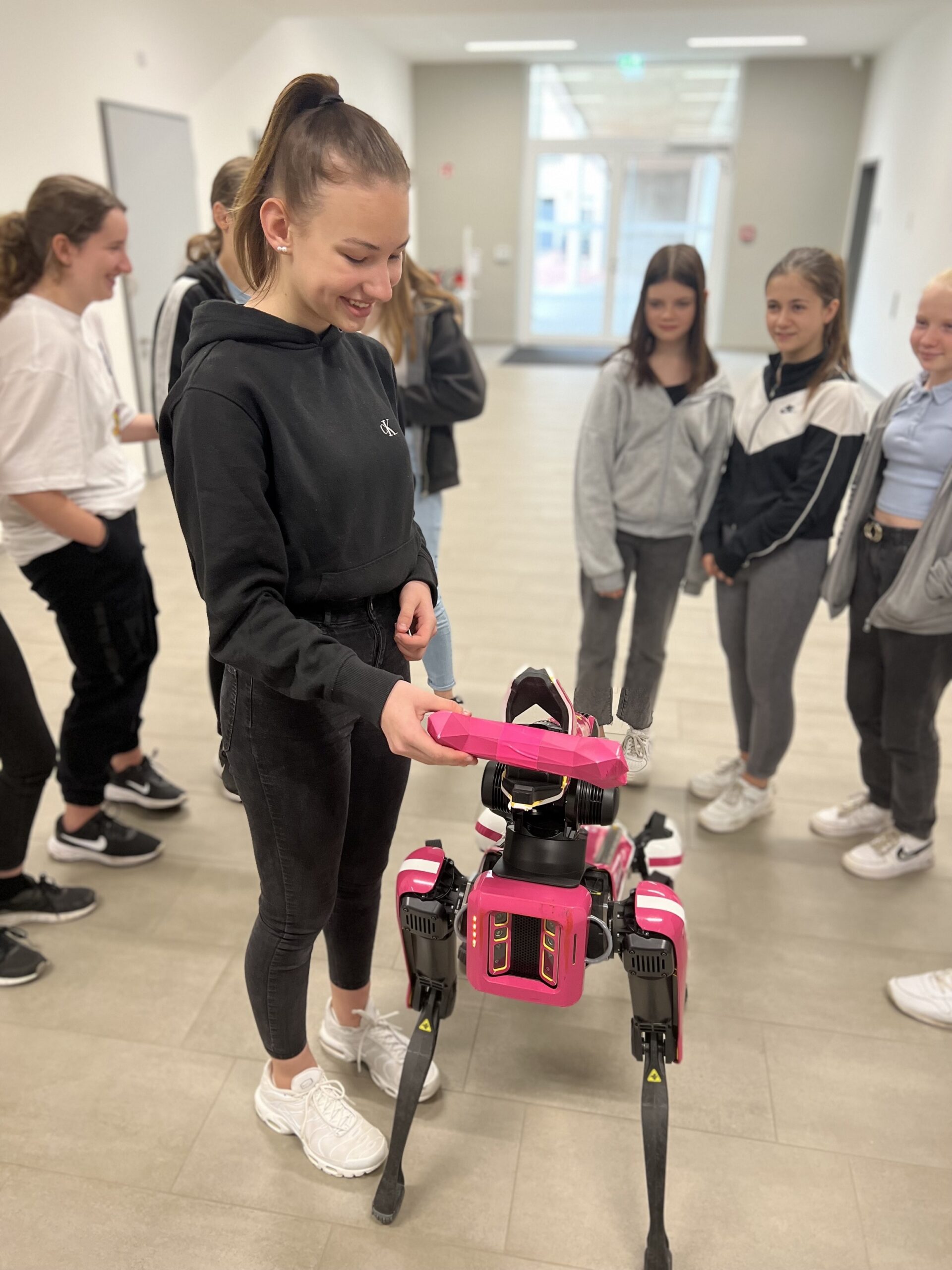 Picture of a group of girls near a robotic dog