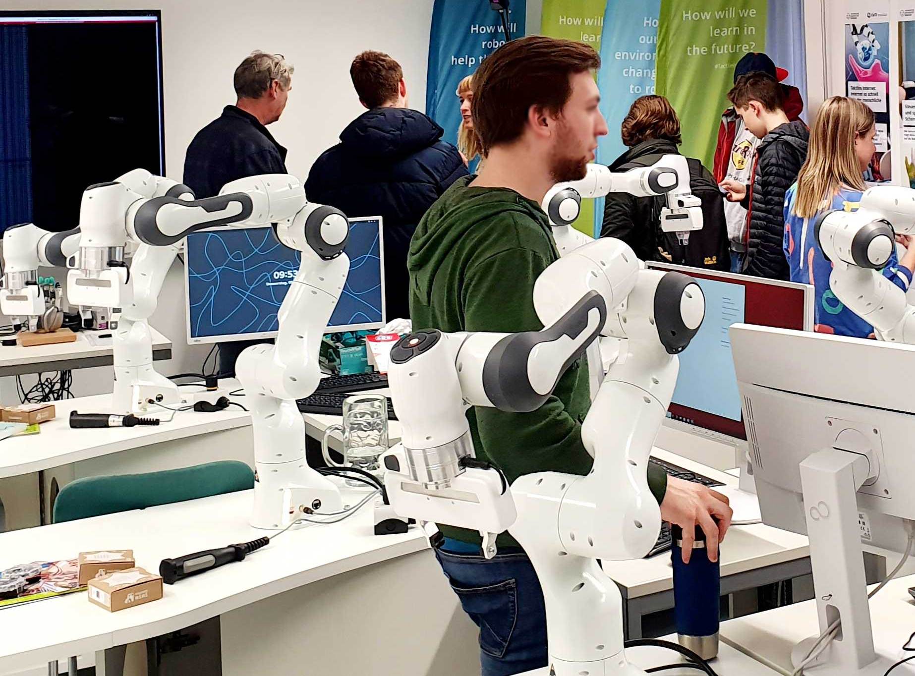 Group image of people visiting a room containing robotic arms