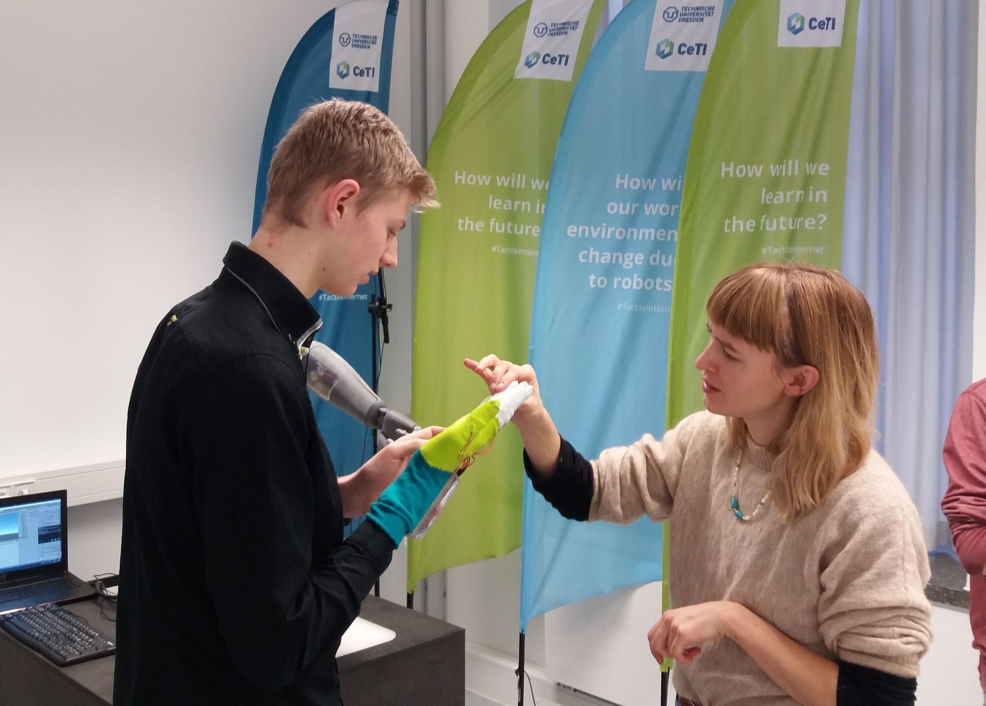 Image of a boy wearing a smart glove and a researcher explaining its functionality