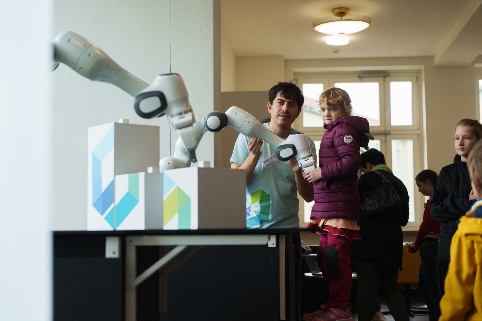 Photograph of a researcher and a little girl moving a robotic arm