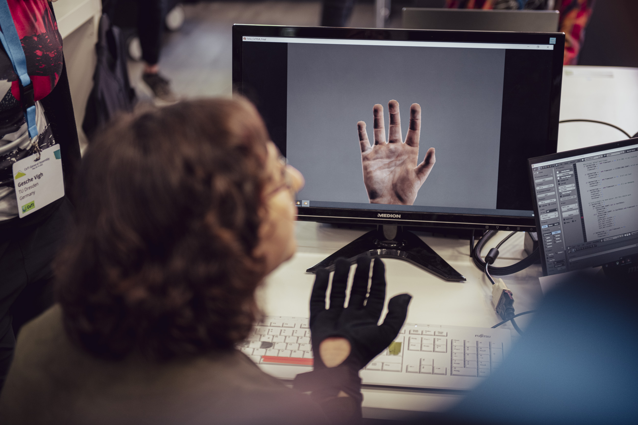 A person wearing a tactile glove and a laptop in front of them that reproduces the person's hand