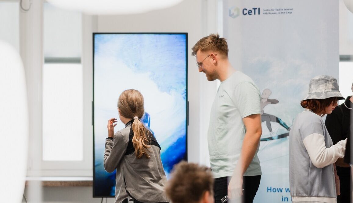 Photograph of a CeTI researcher explaining the surfing demonstrator to a child