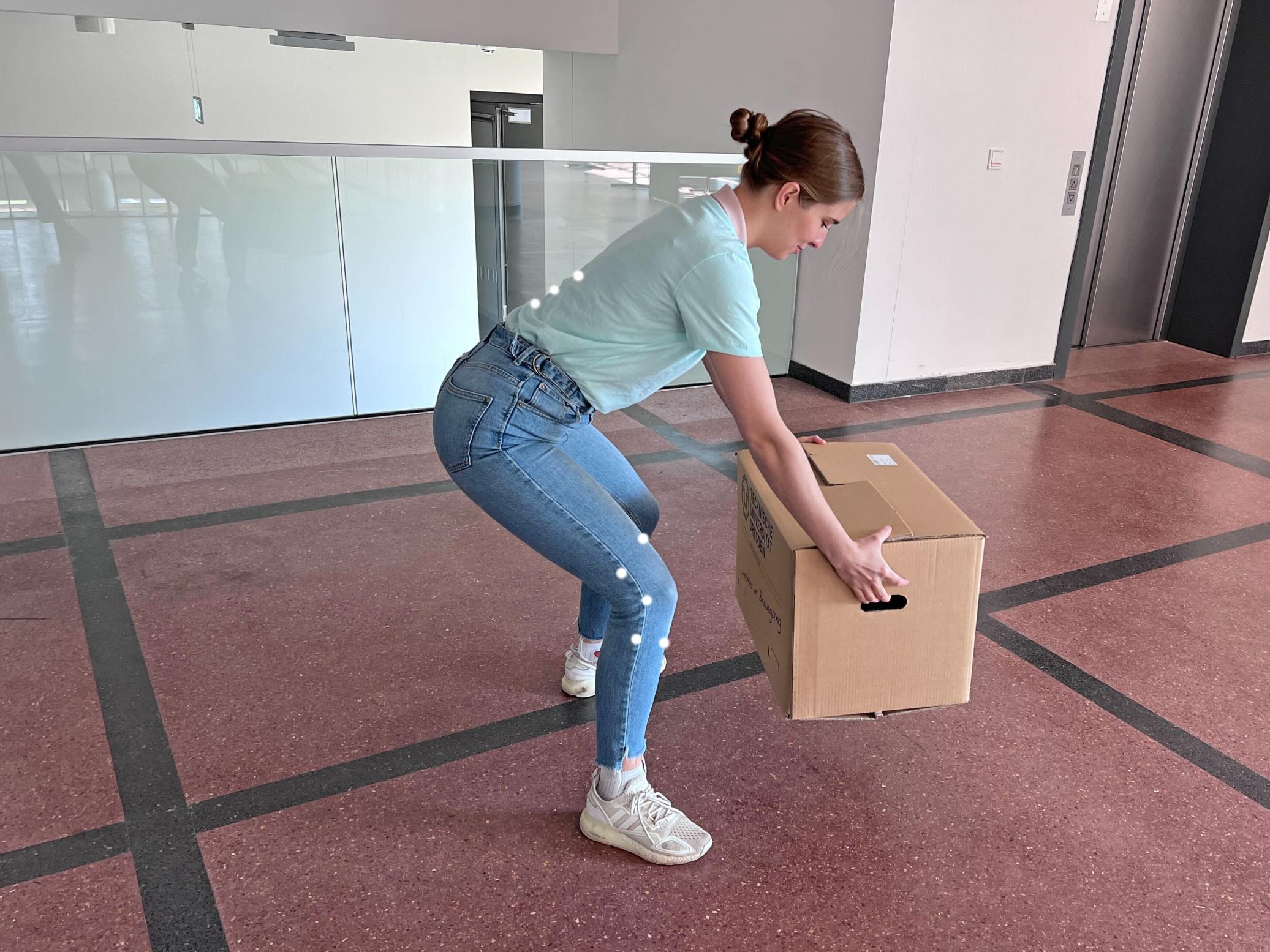 A girl lifting a cardboard box with a correct posture